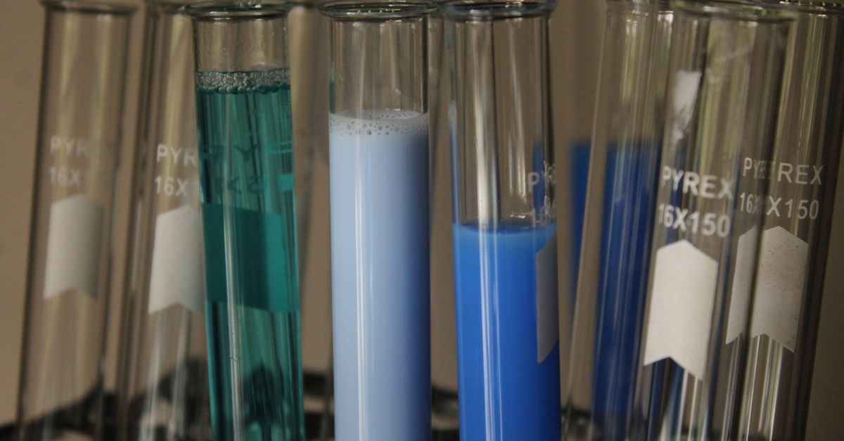 Close-up of colorful chemical solutions in glass test tubes in a laboratory setting.
